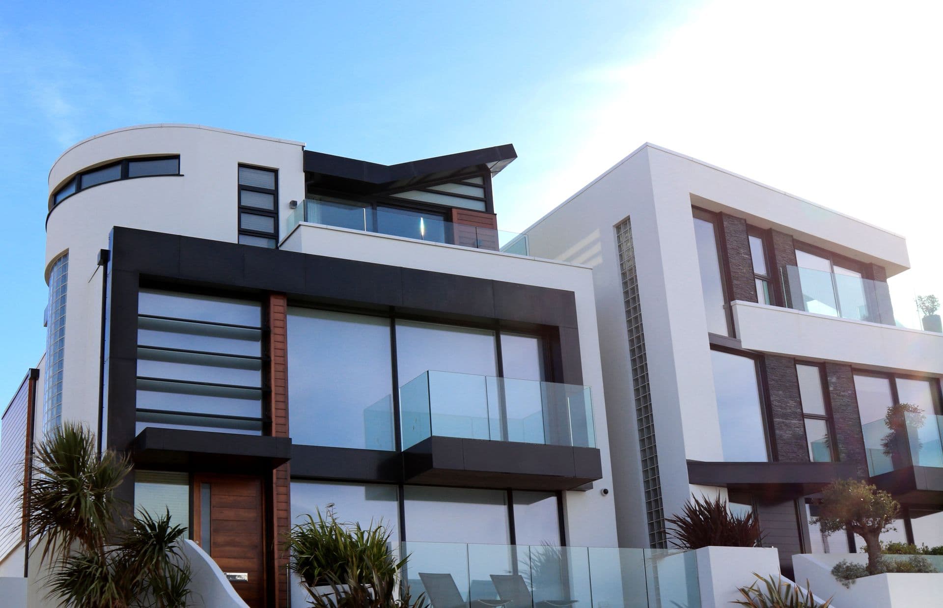 Casas contemporáneas con grandes ventanales, madera y barandas de vidrio