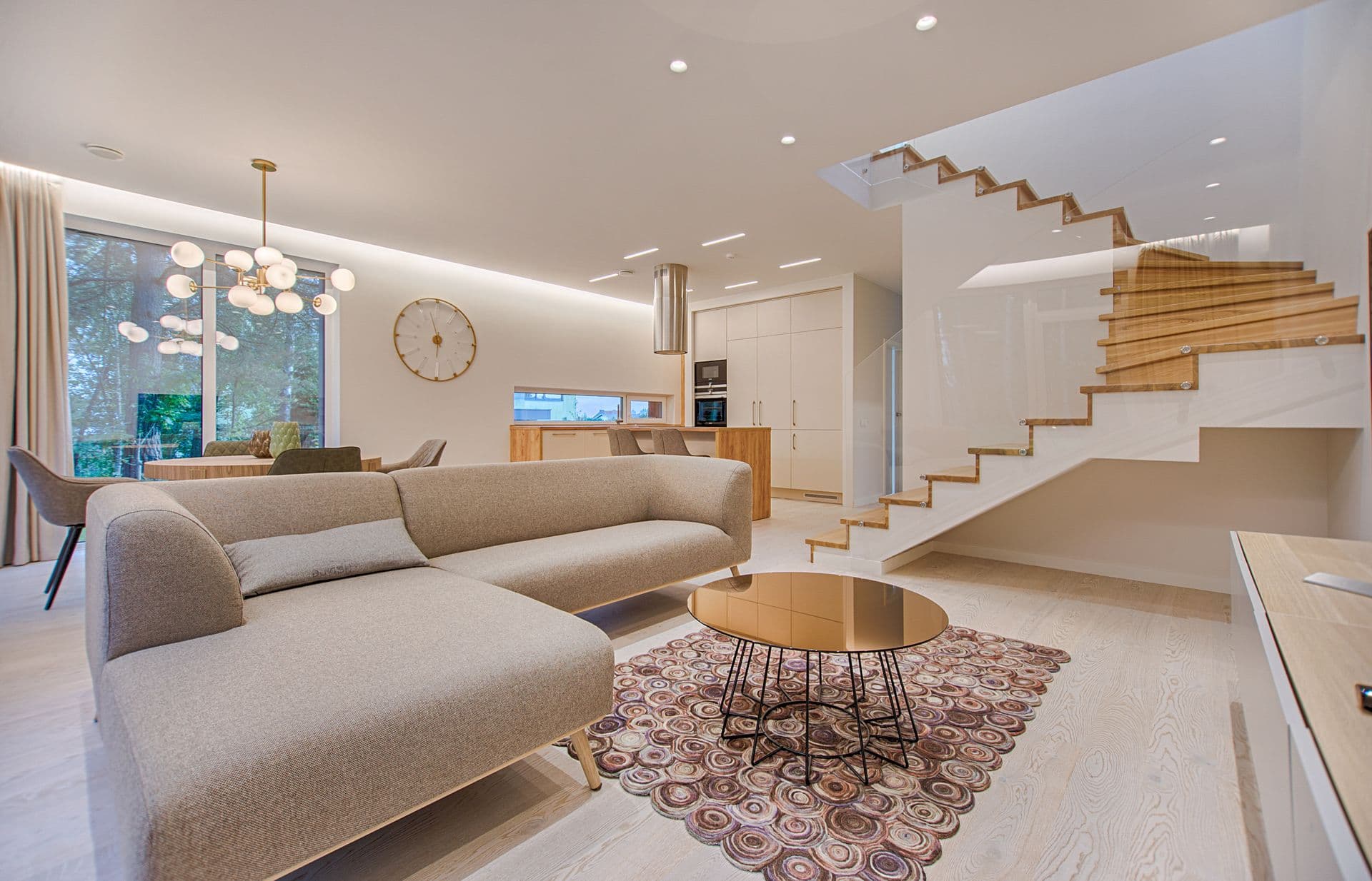 Living contemporáneo con escalera de madera y baranda de vidrio