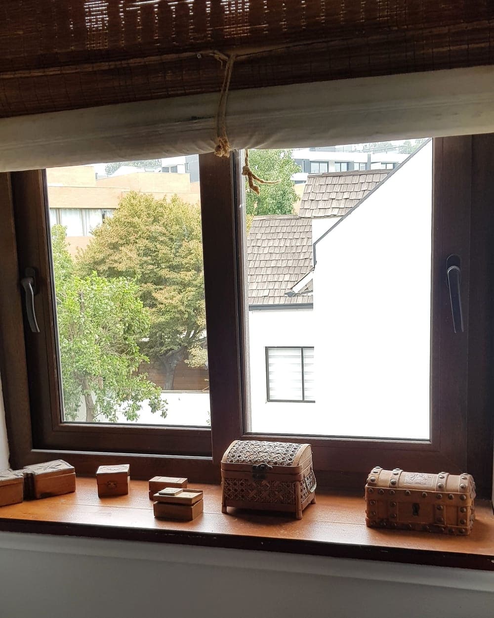 Ventanas de PVC nogal sobre mesón de madera con vista a los techos del barrio