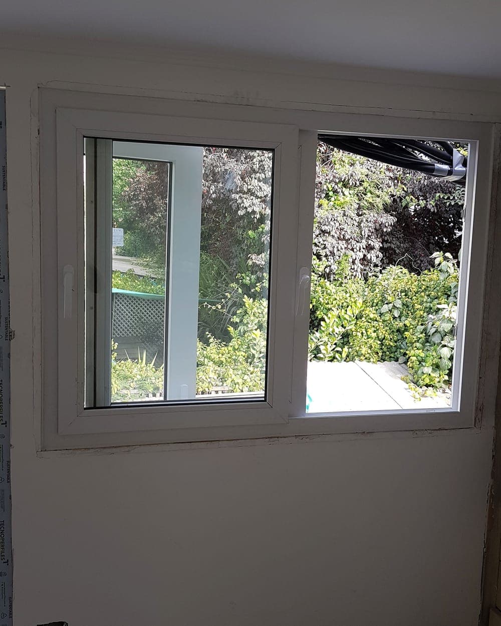 Ventana corredera de PVC blanco con vista a un jardín en Providencia